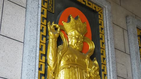 golden statue of a man on the wall of the thien hau temple in chinatown of los angeles, california