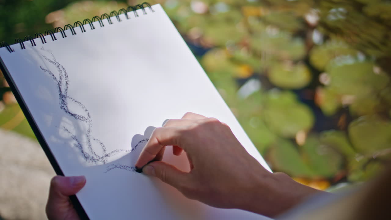 Artist hands drawing sketch at sunshine nature closeup. Woman fingers painting