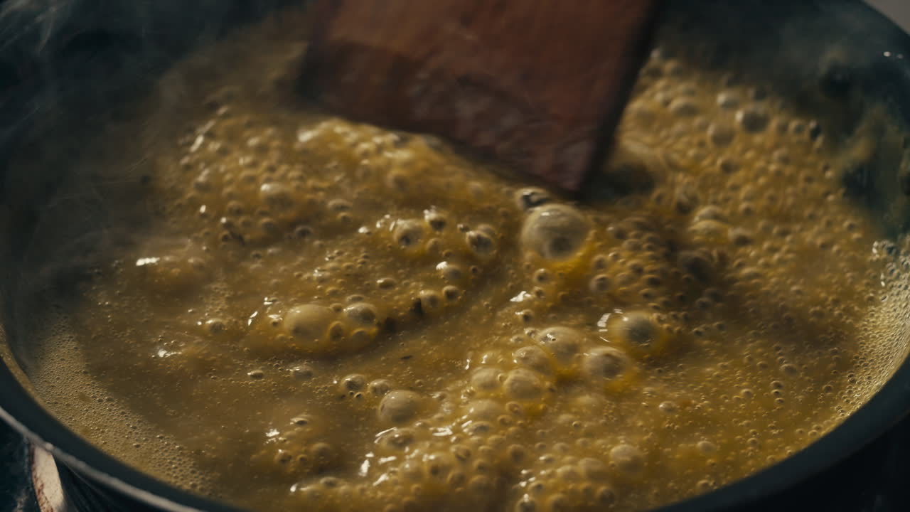 Green boiling sauce texture close-up macro. Cooking green curry with wooden spoon at home.