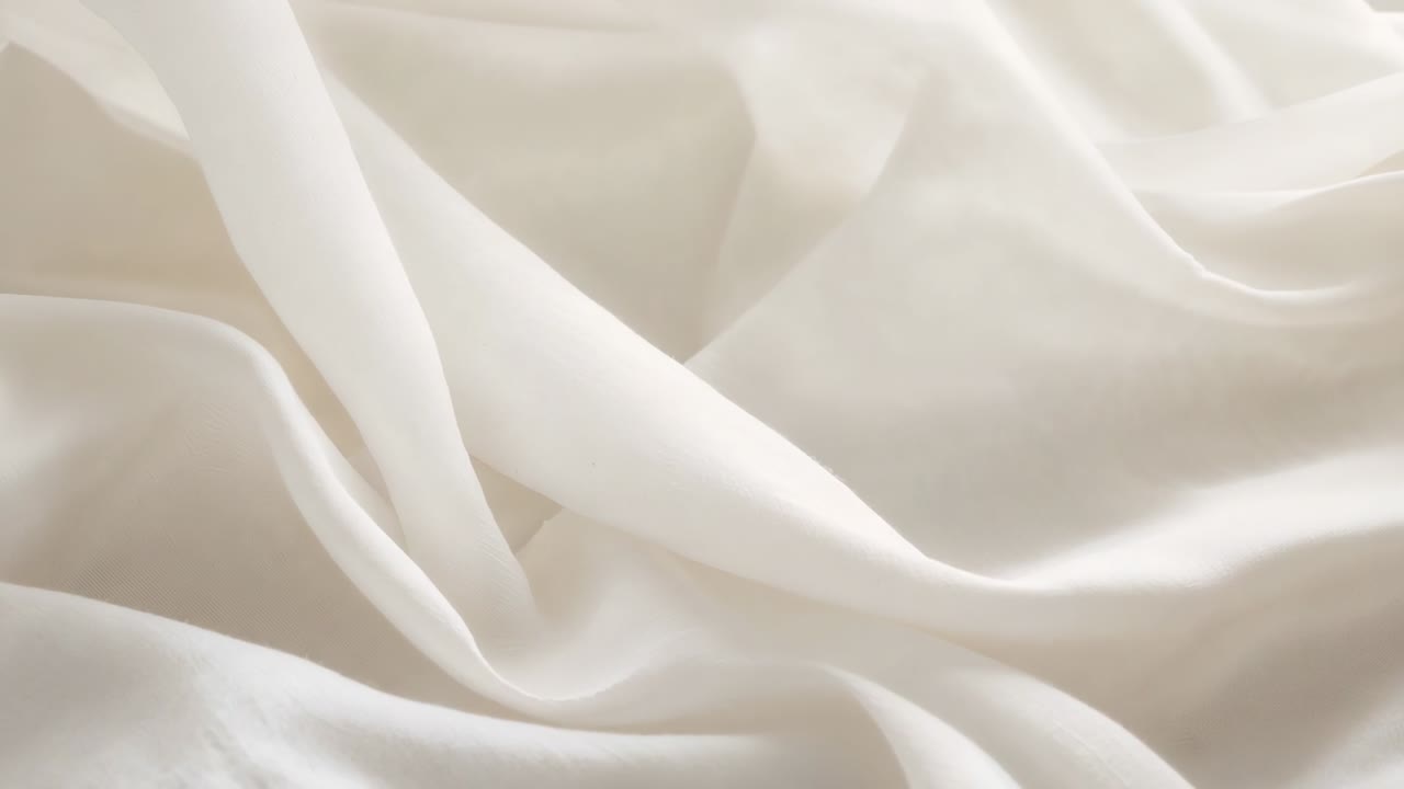 Shifting soft light causing highlights to move across cream fabric on bed, with folds smoothing