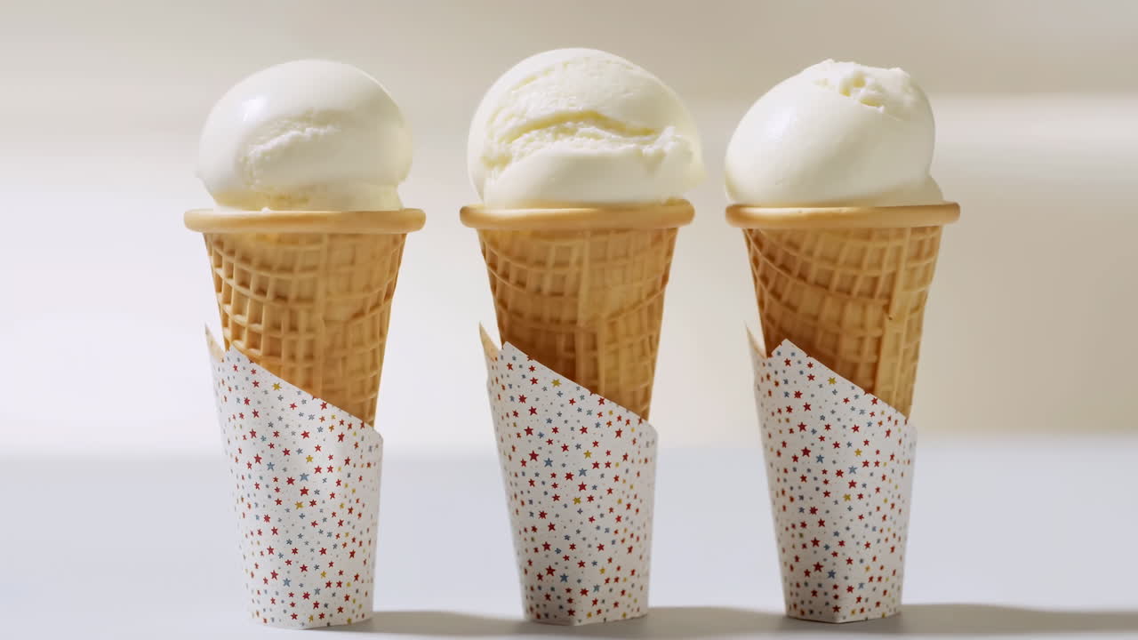 Tre palline di gelato alla vaniglia in coni waffle.
