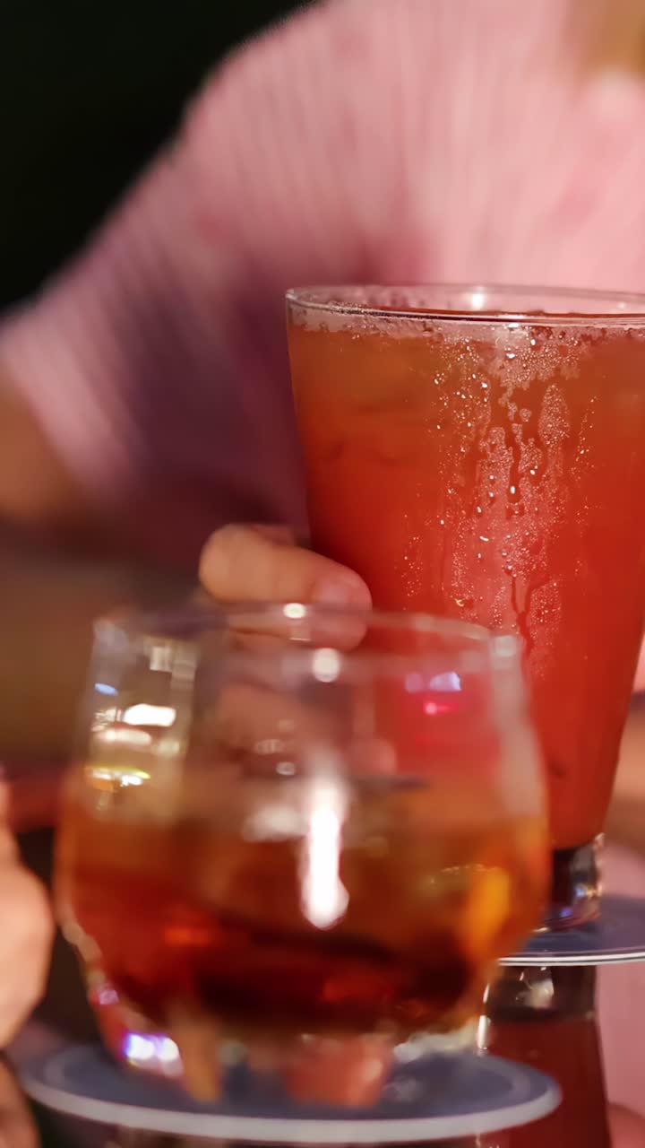 Mano di donna che afferra un cocktail Bloody Mary all'aperto, illuminazione calda, profondità di campo ridotta