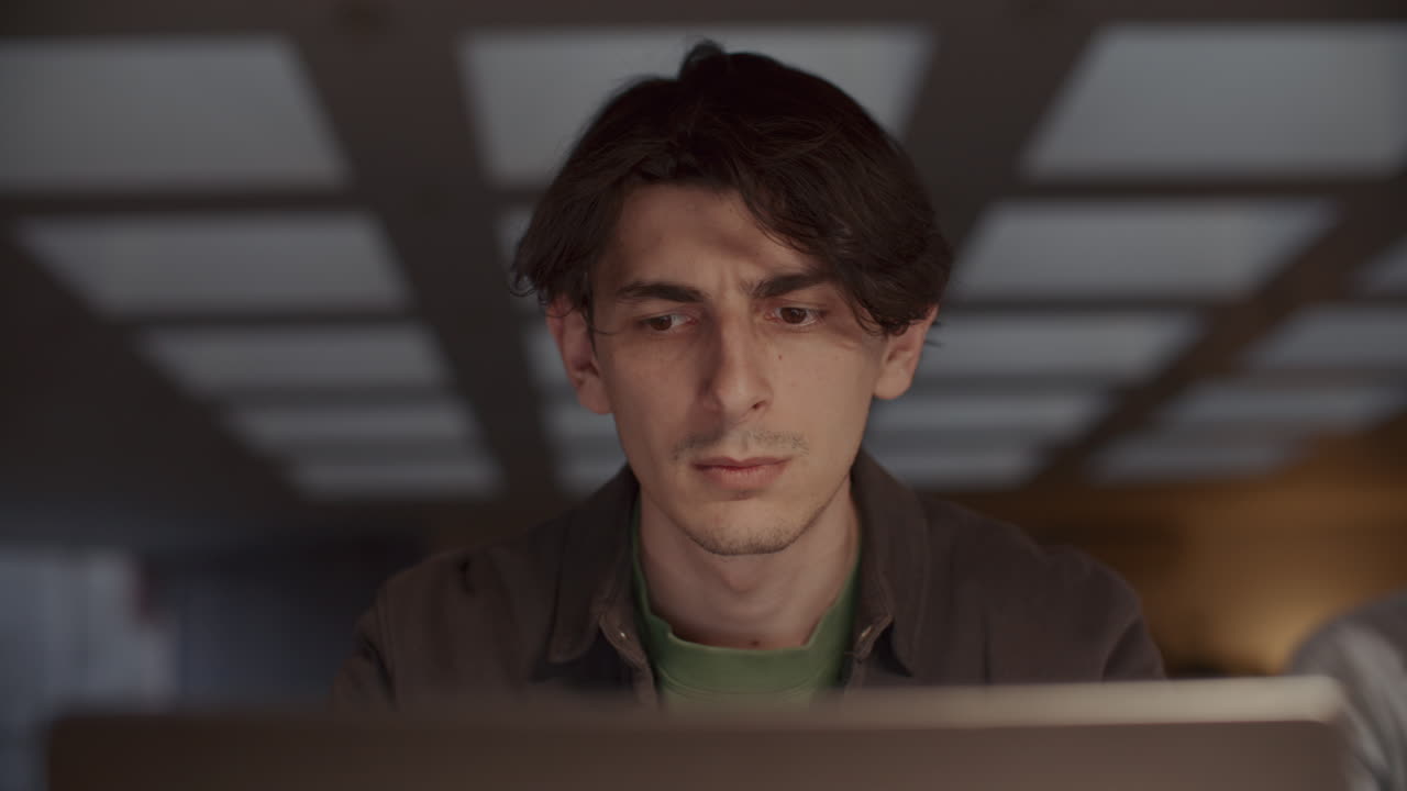 Young Man Typing on Laptop at Office Workplace during Evening