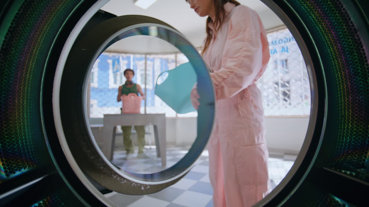 una mujer de primer plano puso la ropa en la máquina. un joven hipster usando una lavandería pública.