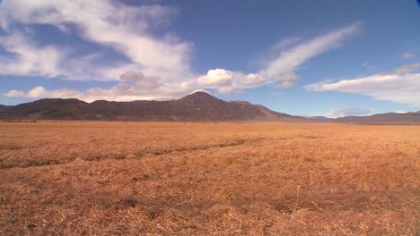 clouds move over a distant mountain behind a field in timelapse