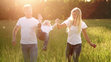 happy family, mom dad and son on an emotional walk. running and enjoying life in a green field in the fresh air, blue sky, nature