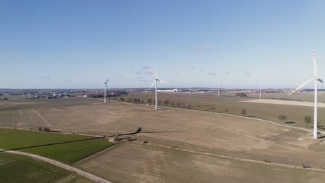 beautiful aerial sunset landscape with lake and windmills or wind turbine on wind farm in rotation to generate electricity energy, 4k