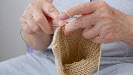 close up of knitting, grandmother knits woolen socks to her grandson. the old woman's hands are covered with marches from many years of work