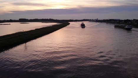 Vista-Aérea-De-La-Puesta-De-Sol-Sobre-El-Río-Noord-Del-Buque-De-Carga-Que-Viaja-Más-Allá-De-La-Reserva-Natural-De-Crezeepolder-En-Ridderkerk-En-Países-Bajos