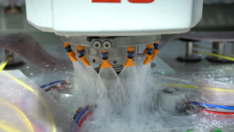 closeup of cnc machine with a water cooling system milling the edges of a small glass plate