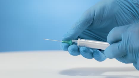 doctor with gloves attaches needle to medical injection syringe in slow motion