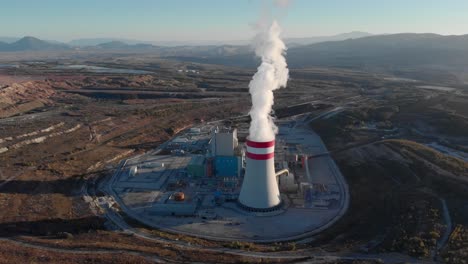 fast aerial orbit smoke from coal fired power station plant cooling towers emitting steam smoke sunset