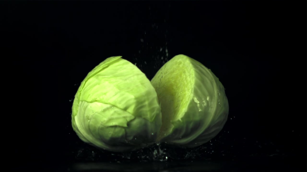 Fresh Green Cabbage Falling and Splitting in Water in Slow Motion