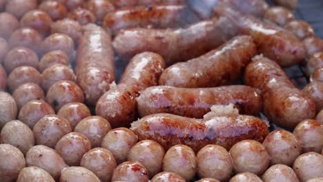 grilling sausages surrounded by small potatoes