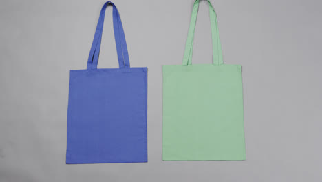 Primer-Plano-De-Bolsas-Azules-Y-Verdes-Sobre-Fondo-Gris,-Con-Espacio-Para-Copiar,-Cámara-Lenta