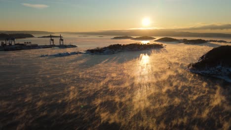 sonnenuntergang über dem hafen in der nähe von bjorvika, oslo mit nebel, der über dem wasser schwebt