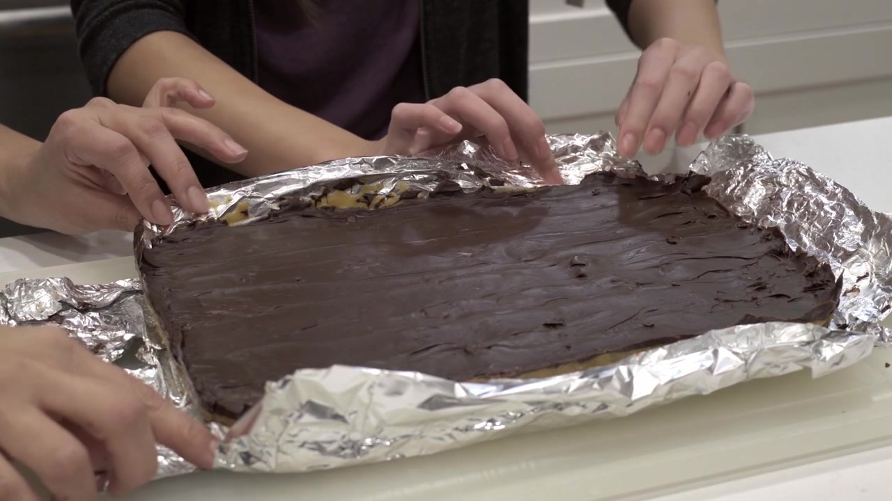 Una madre e una figlia rimuovono il biscotto millionaire shortbread finito dalla carta stagnola.