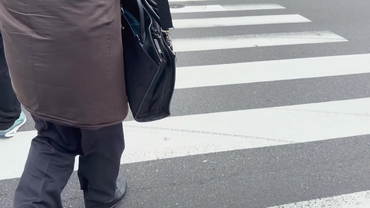 Low angle shot of people walking across a zebra crosswalk on a city street