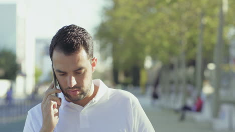 Hombre-Barbudo-Enfocado-Hablando-Por-Teléfono-Durante-Un-Paseo-Por-Las-Calles-De-La-Ciudad.