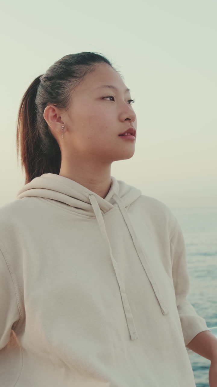 パーカーを着て海を眺める女性