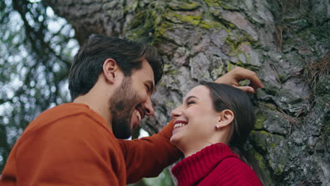 una pareja riendo de pie en un árbol del bosque pasando felices vacaciones en primer plano vertical