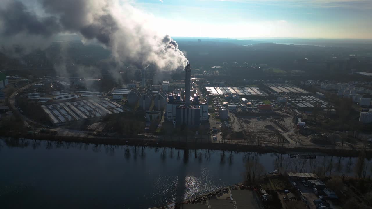large industrial power plant emitting large amounts of smoke over the city Berlin next to a river on a sunny day. Nice aerial view flight drone shot footage from above