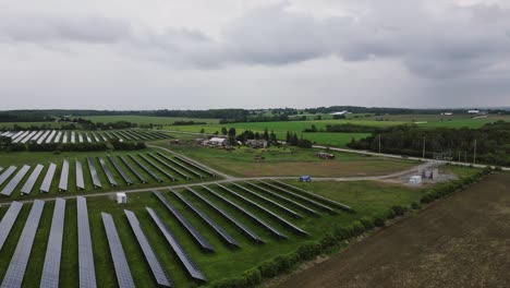 Solar-Power-Station-In-Green-Field-On-A-Cloudy-Day---drone-shot