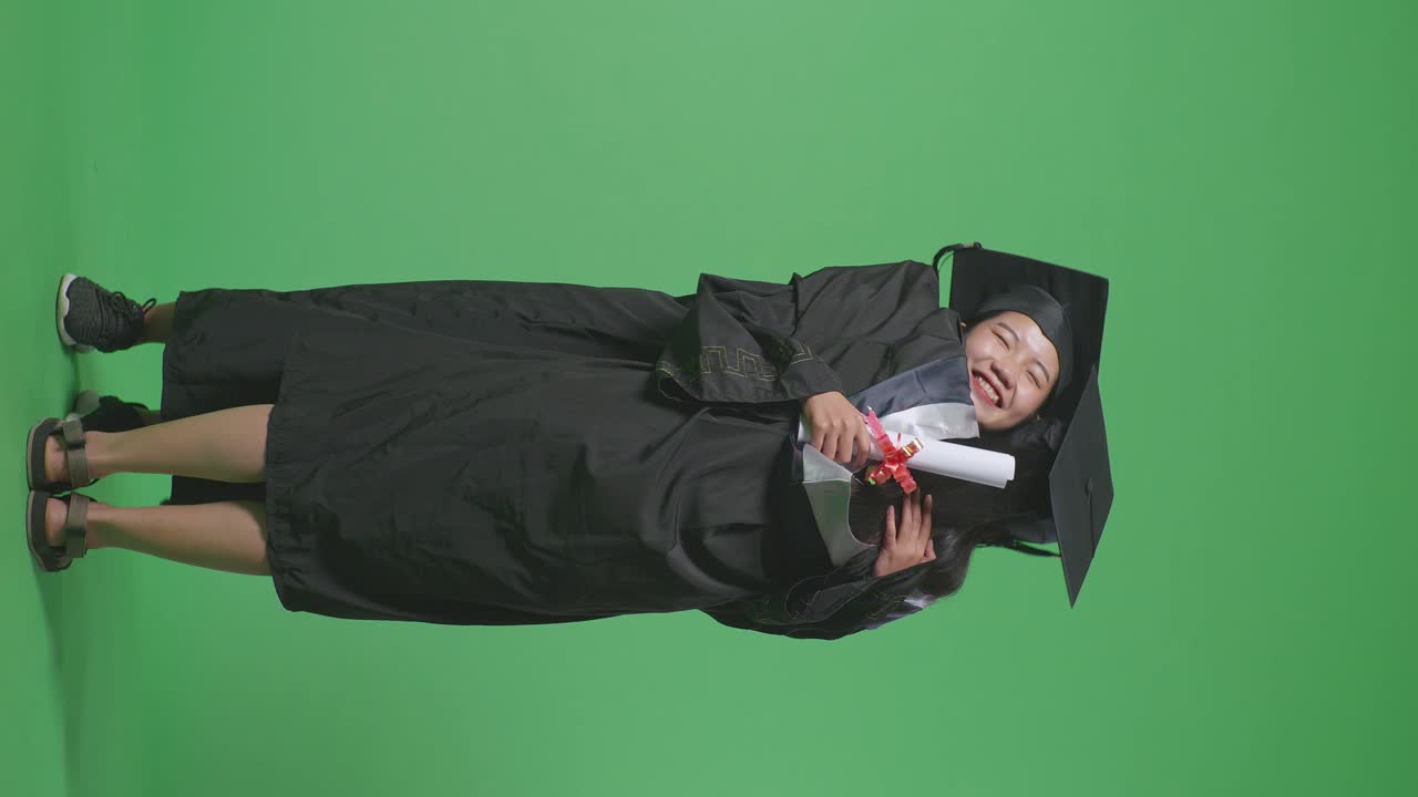 졸업 의상 을 입은 여자 가 졸업 증명서를 들고 있다