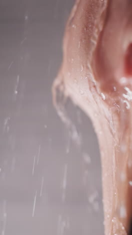 woman holds face under running water in shower closeup. pleasured lady enjoys warmth of pure sprays in home bathroom. recreation after hard day