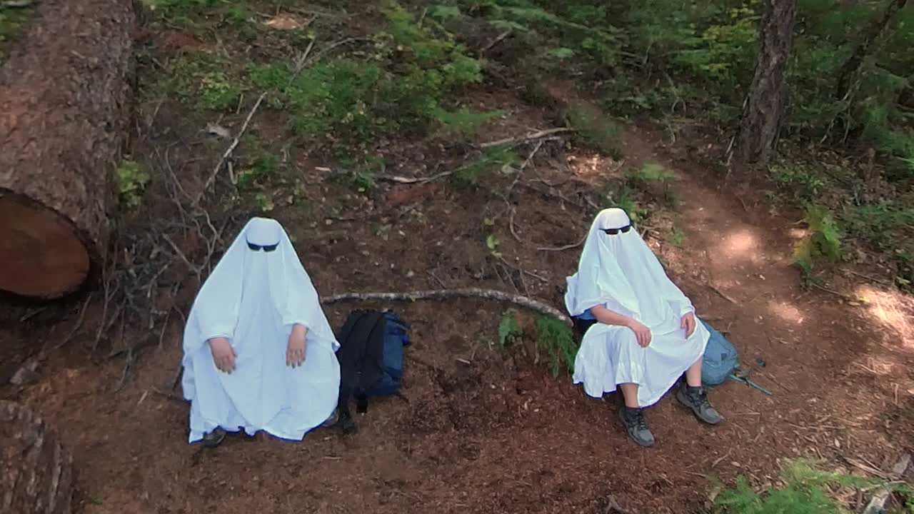 Two people dressed up as ghosts sitting in the Oregon rain forest
