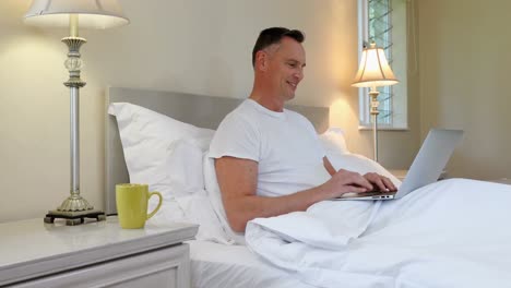 hombre usando computadora portátil mientras se relaja en la cama 4k