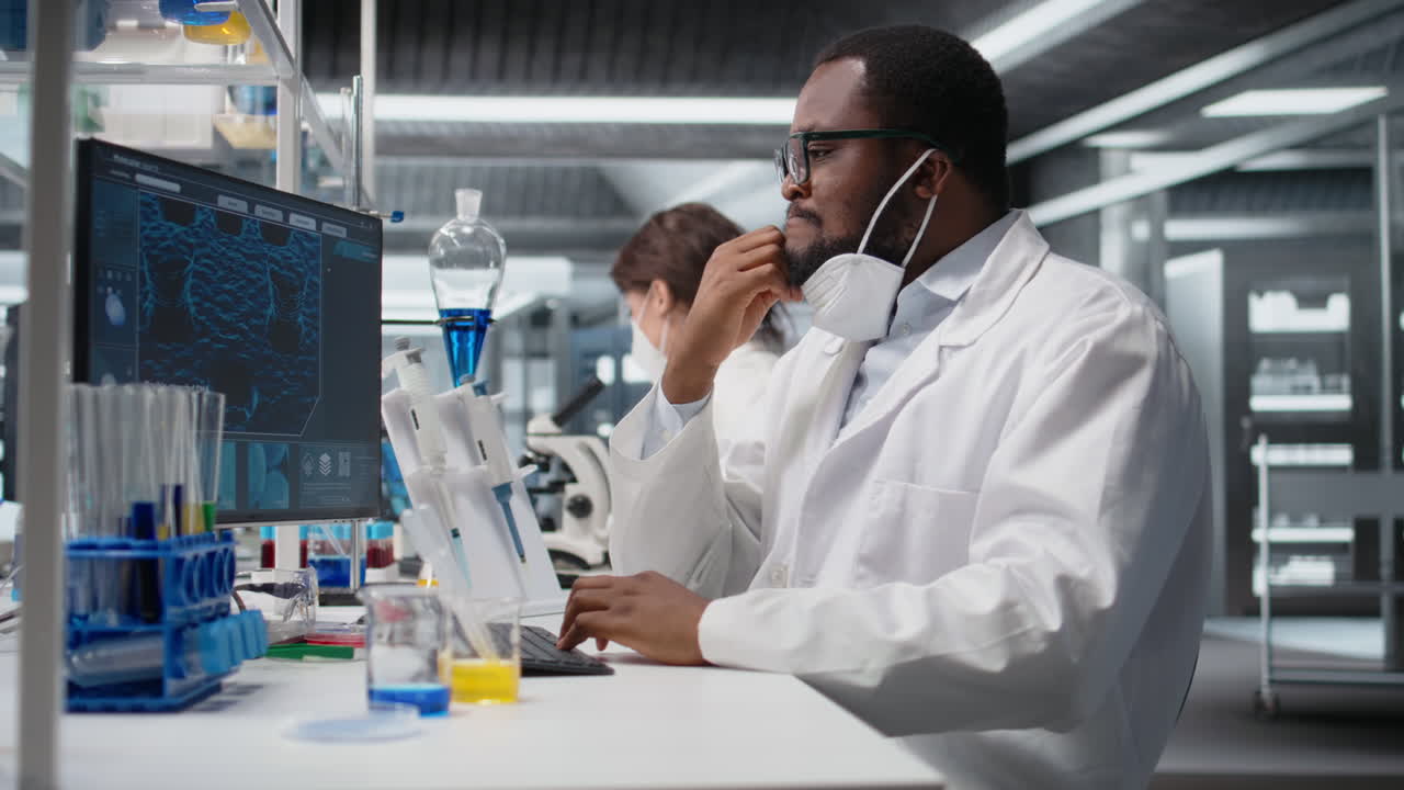 Vertical video Researcher wearing medical mask in sterile laboratory using computer