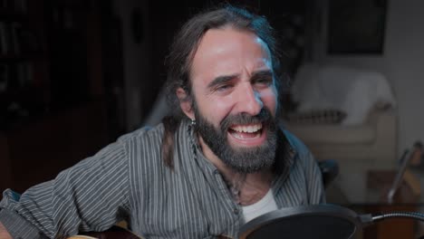 man singing and playing acoustic guitar at home