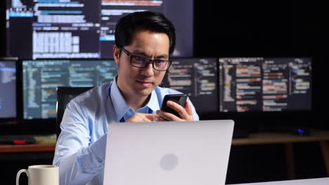 man working on computer and phone at night