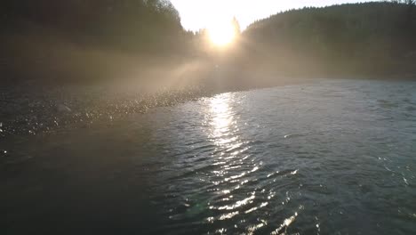 drone in riverbed fog cloud haze flying backwards low over river rapids