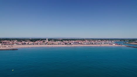 Toma-Aérea-De-Hermosas-Aguas-Azules,-Una-Impresionante-Playa-Y-Un-Pequeño-Pueblo