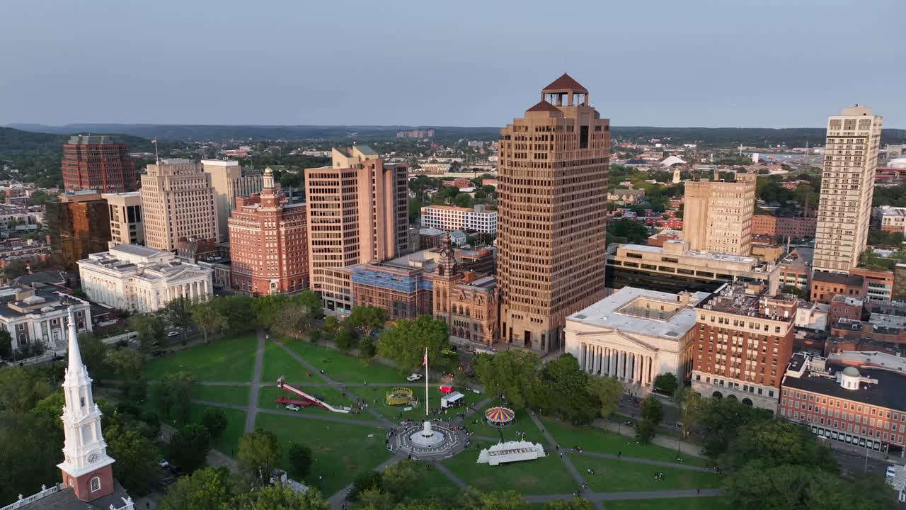 Green Park with American flag on flagpole in front of New Haven Skyline. Sunlight in summer season. American town in Connecticut. Aerial wide shot