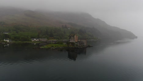 misty low fog gradually enveloping iconic eilean donan castle, revealing dramatic scottish highland landscape with ethereal atmospheric conditions