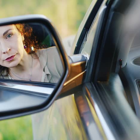 Beautiful-Brunette-Woman-Looking-At-Sideview-Mirror-Preening-Her-Hair-Before-Driving-Car-Close-Up