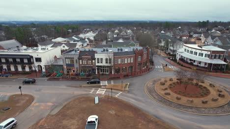 Aerial-of-cars-leaving-roundabout-in-front-of-small-town-shops-and-eateries-at-Moss-Rock-Preserve-in-Hoover,-Alabama