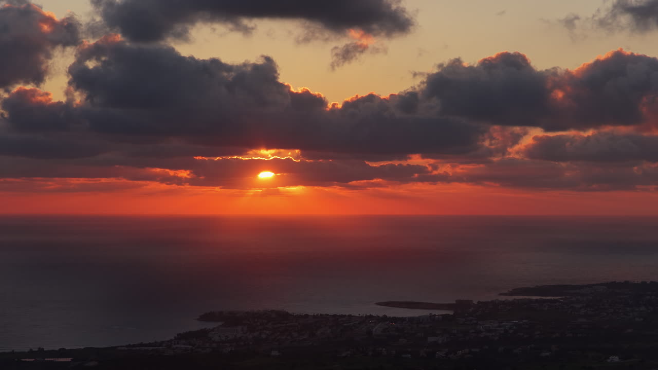 Drohnenaufnahme eines goldenen Sonnenuntergangs, der sich auf dem ruhigen Mittelmeer spiegelt.