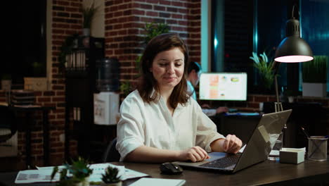 Portrait-of-smiling-accountant-sitting-at-office-desk-in-front-of-laptop