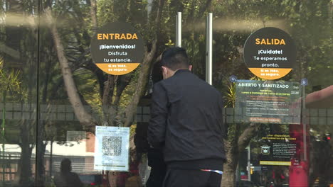 Plano-Medio,-Una-Persona-Está-Escaneando-Un-Código-Qr-En-La-Entrada-De-Un-Restaurante