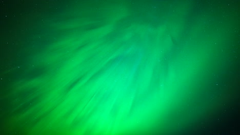 green and yellow northern lights sparkle and shimmer in starry night sky, upward angle