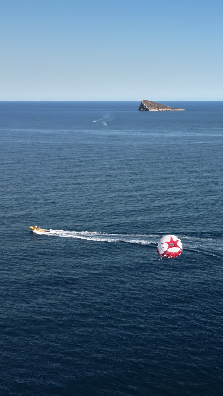People parasailing on the Mediterranean Sea in Benidorm, Spain. Vertical