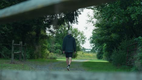 Man-scratching-head-walking-down-dirt-road