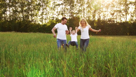 happy family: father, mother and son, running in the field dressed in white t-shirts