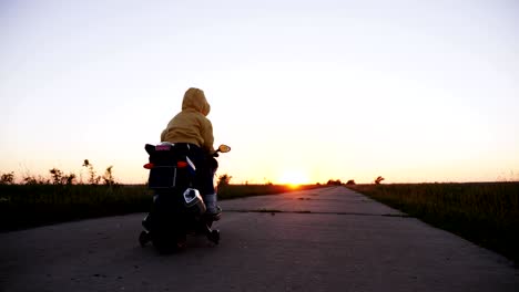 a boy of three years riding a toy motorcycle on a road