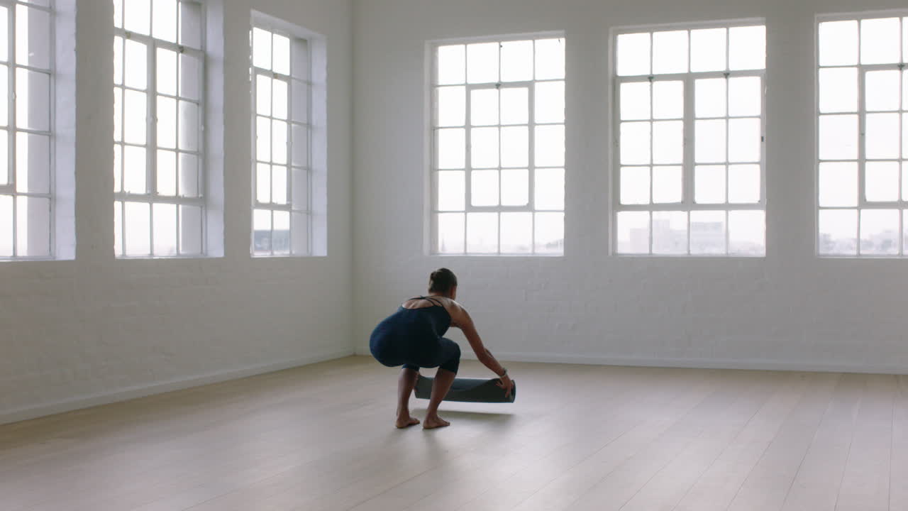 mujer de yoga saludable preparando colchoneta de ejercicios lista para la práctica de meditación temprano en la mañana en el gimnasio