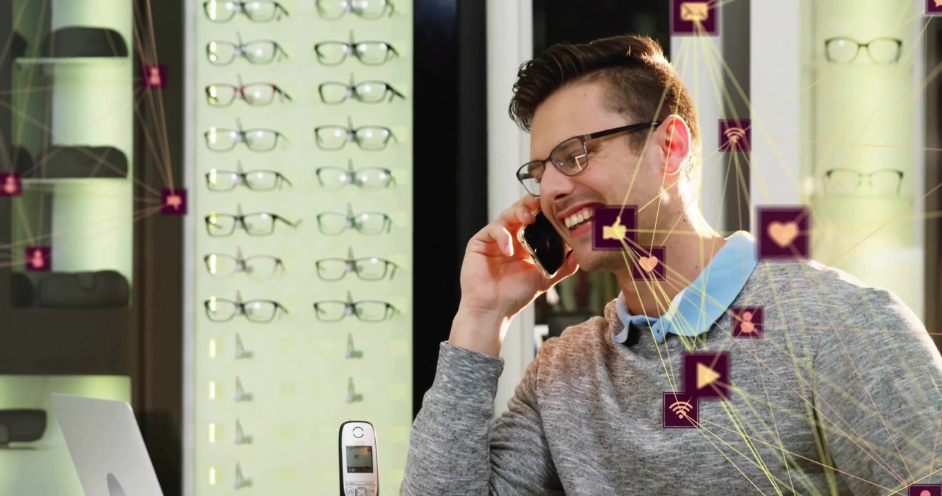 Animation of connected icons globes, smiling caucasian man talking on smartphone at optical store